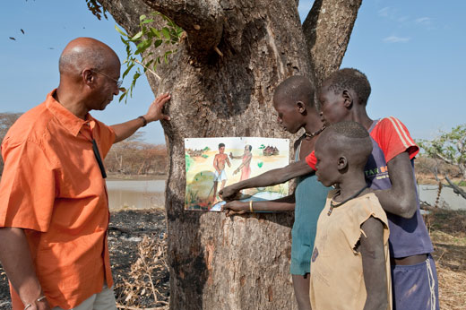 Donald Hopkins, vice president of health programs at The Carter Center, shows South Sudanese children how to prevent Guinea worm disease when they visit their local water source.