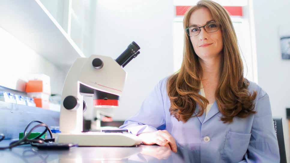 female faculty member posing with microscope