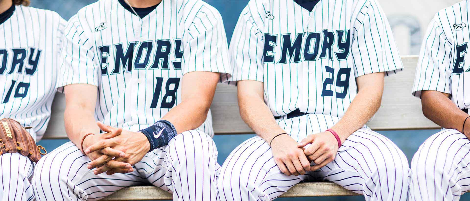 close up of baseball players uniforms while they sit in dugout