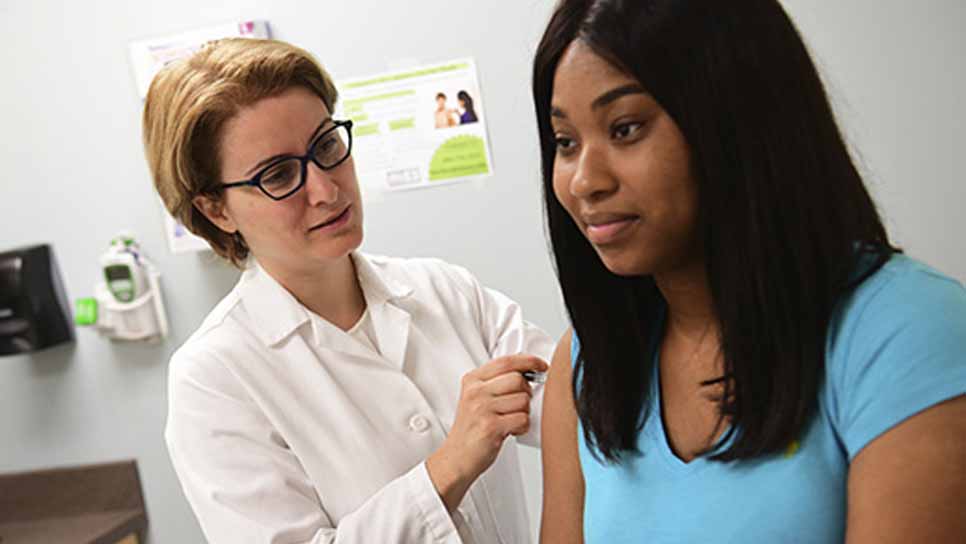 researcher draws blood from a patient for study