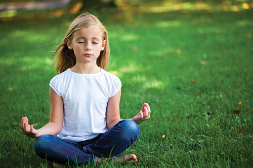 Girl sitting on grass in lotus position meditating