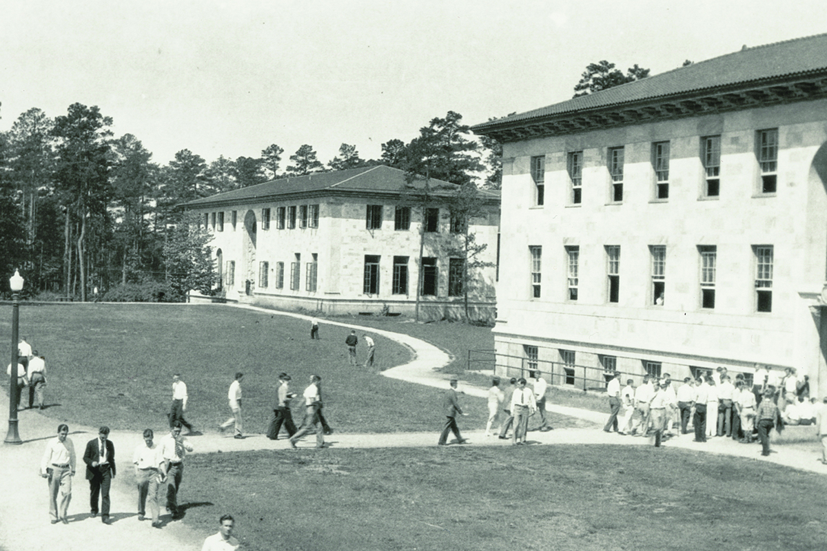 Black and white image of students walking on dirt pathways on the Emory Quadrangle in the early 1900s.