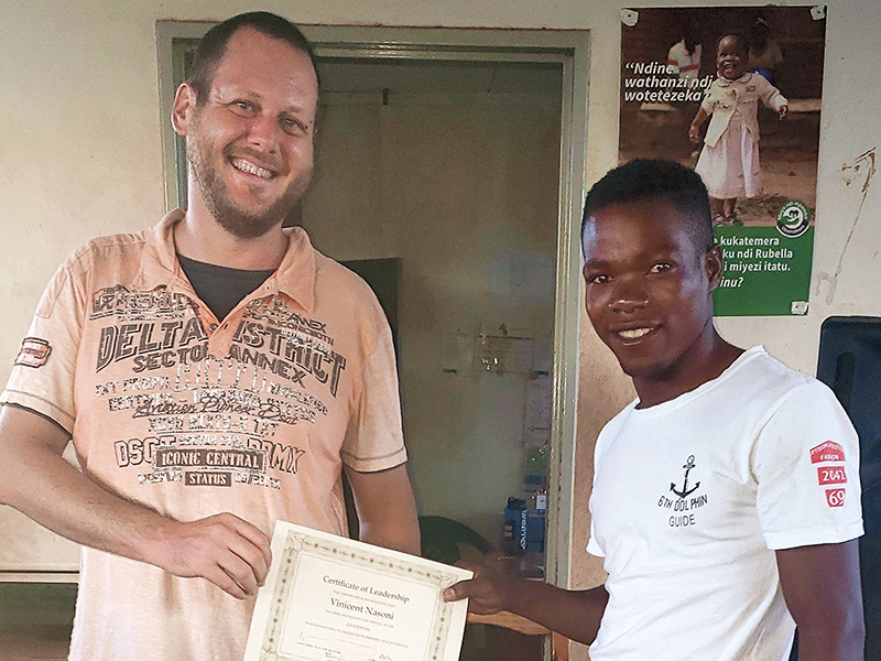 A bearded mans presents a teenage boy with a certificate of leadership.