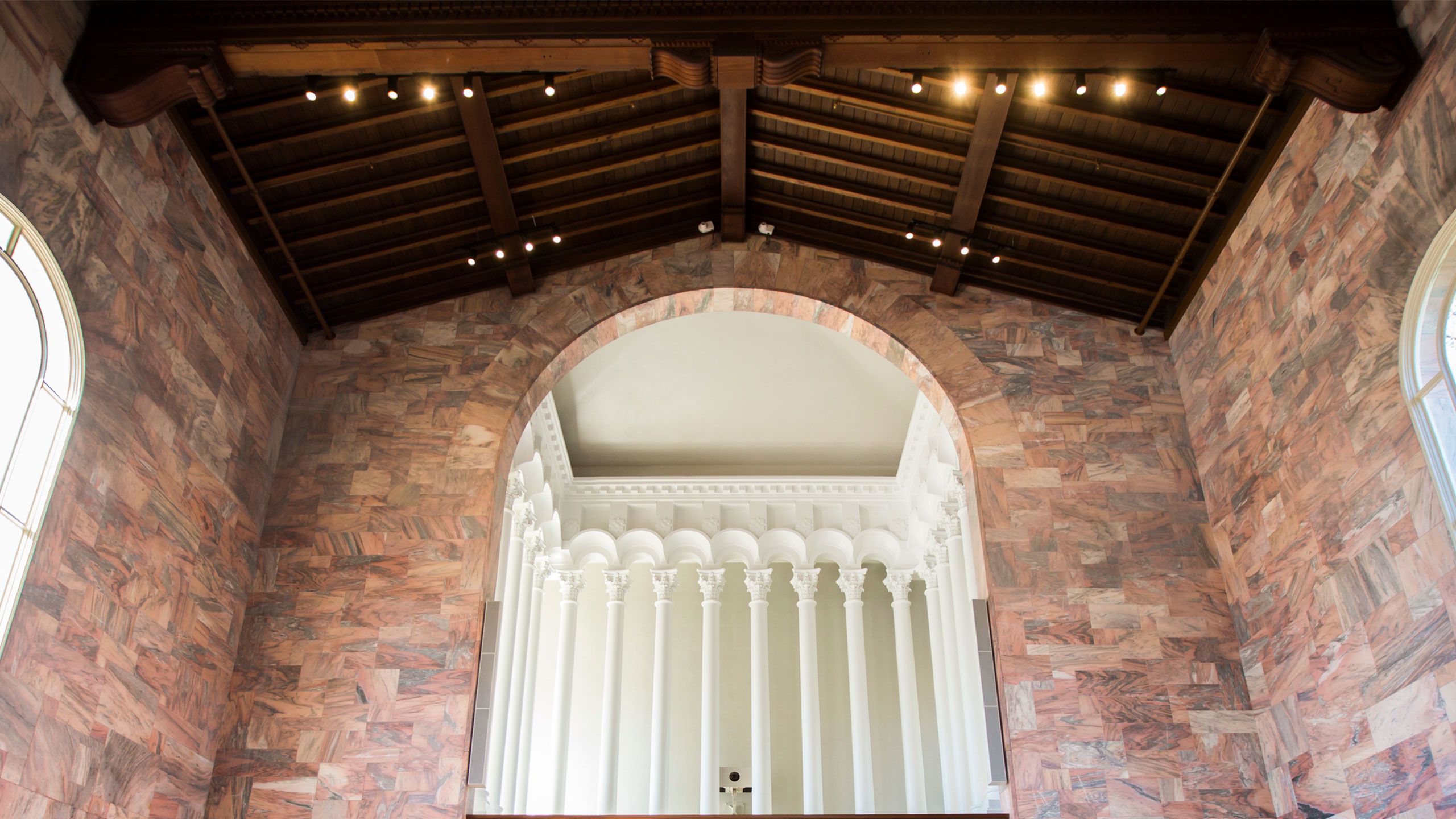 An interior view of Convocation Hall highlighting a multi-story arch cutout reaching the exposed beams in the ceiling