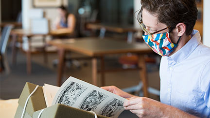 masked student reading a book in the library