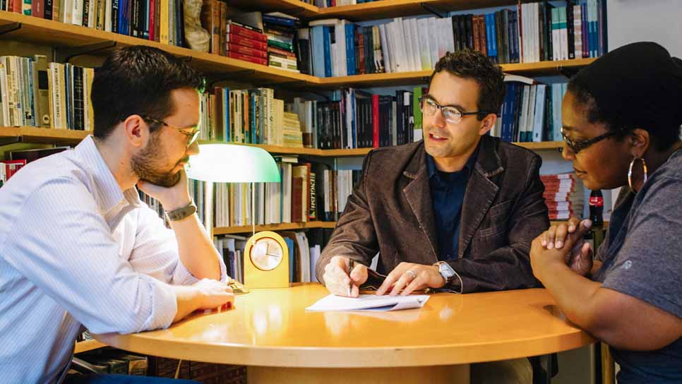 professor discussing an academic paper with two students