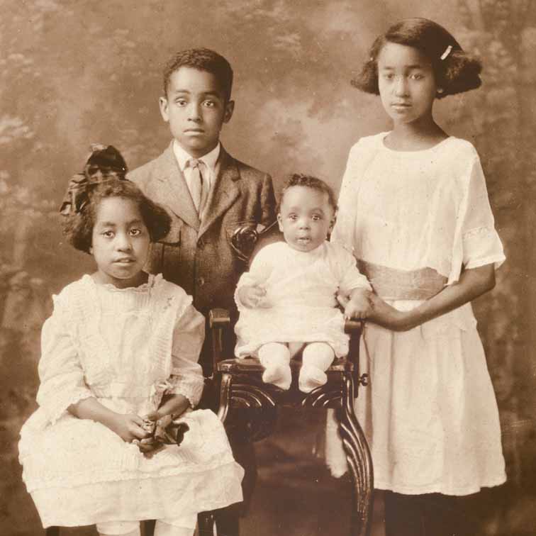 sepia-toned formal photograph of four African American children