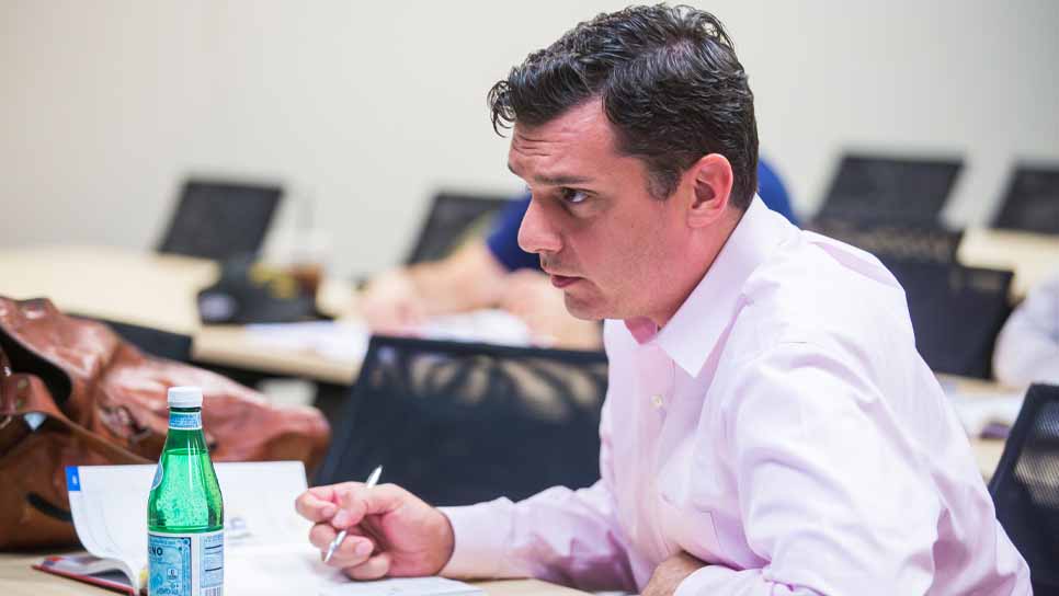 man in pink shirt pays attention in class