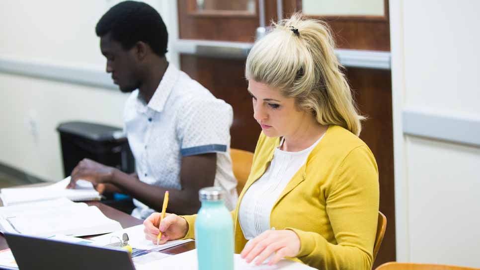 student in yellow cardigan does work in class