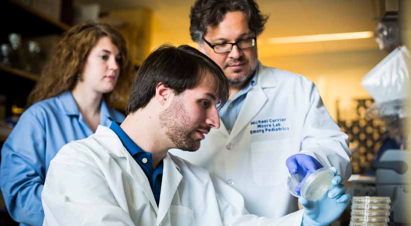 three students examine lab experiment