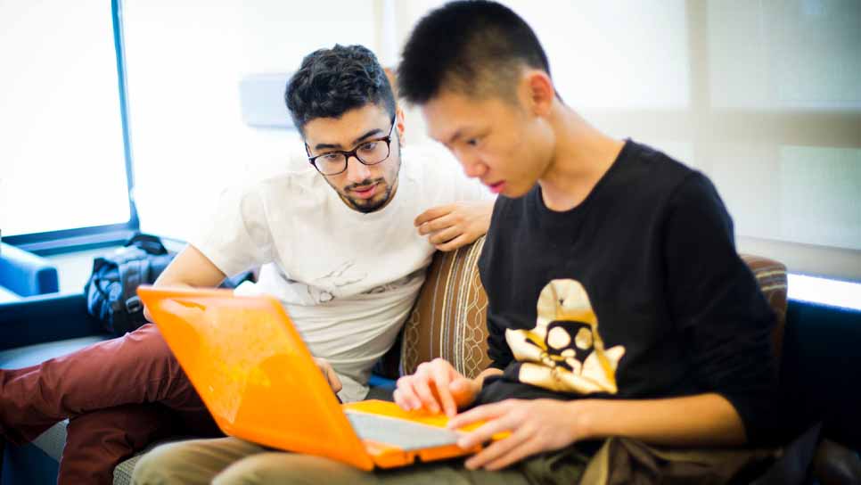 two students working on a laptop