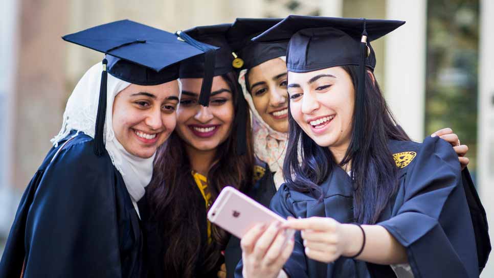 students in caps and gowns taking a selfie at graduation