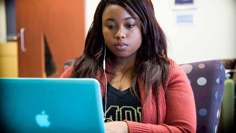 female student working on a blue laptop