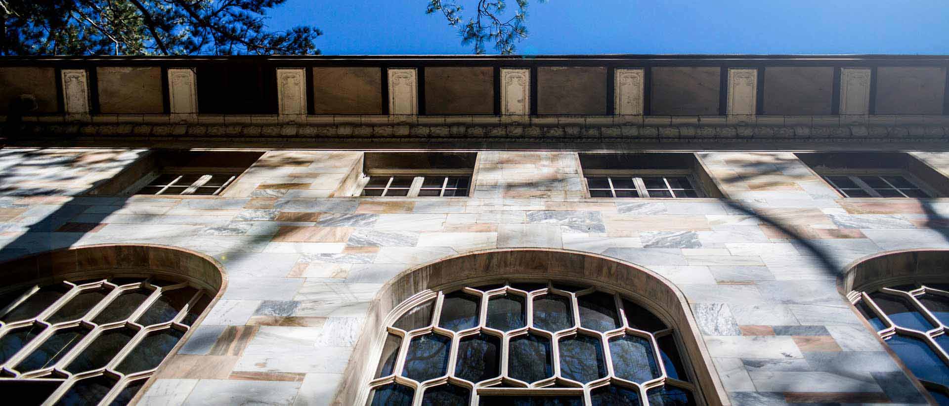 looking up at the front of a marble building with a blue sky behind