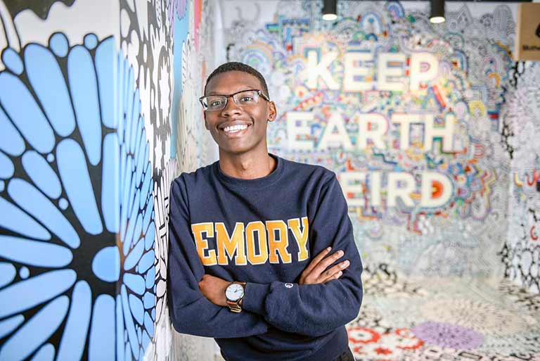 student smiling with emory shirt on