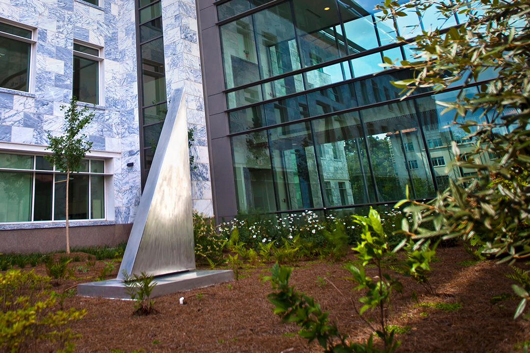 stainless steel sundial triangle-shaped sculpture in a garden outside a building