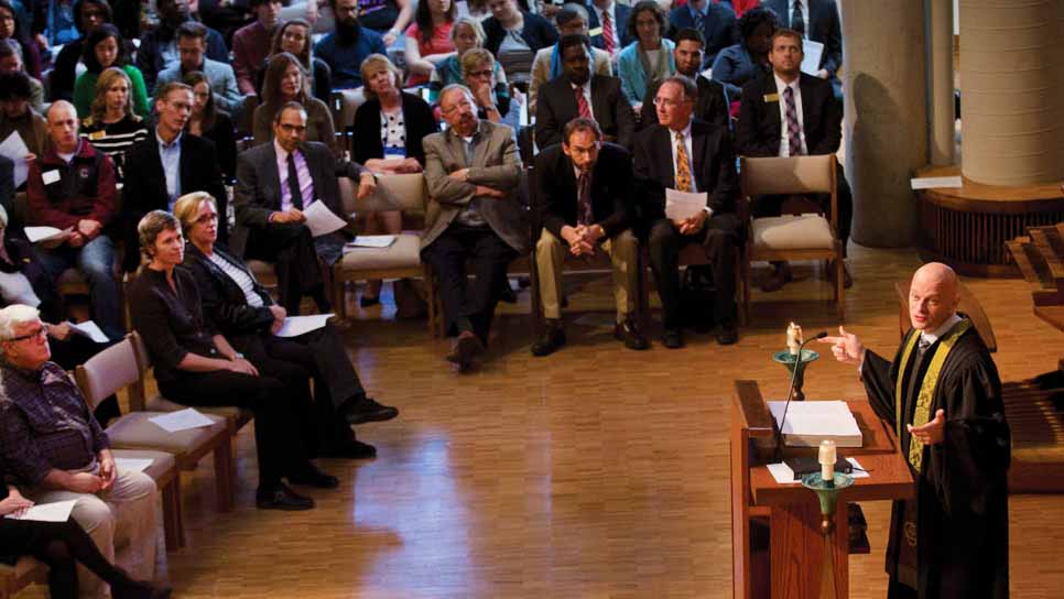 chaplain preaching in a white robe with green trim