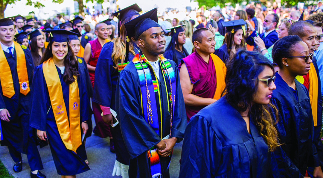 crowd of smiling graduates in cap and gown at graduation