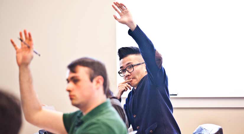students sitting in class raising their hands