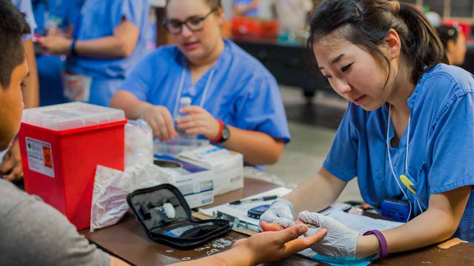 students in scrubs taking blood