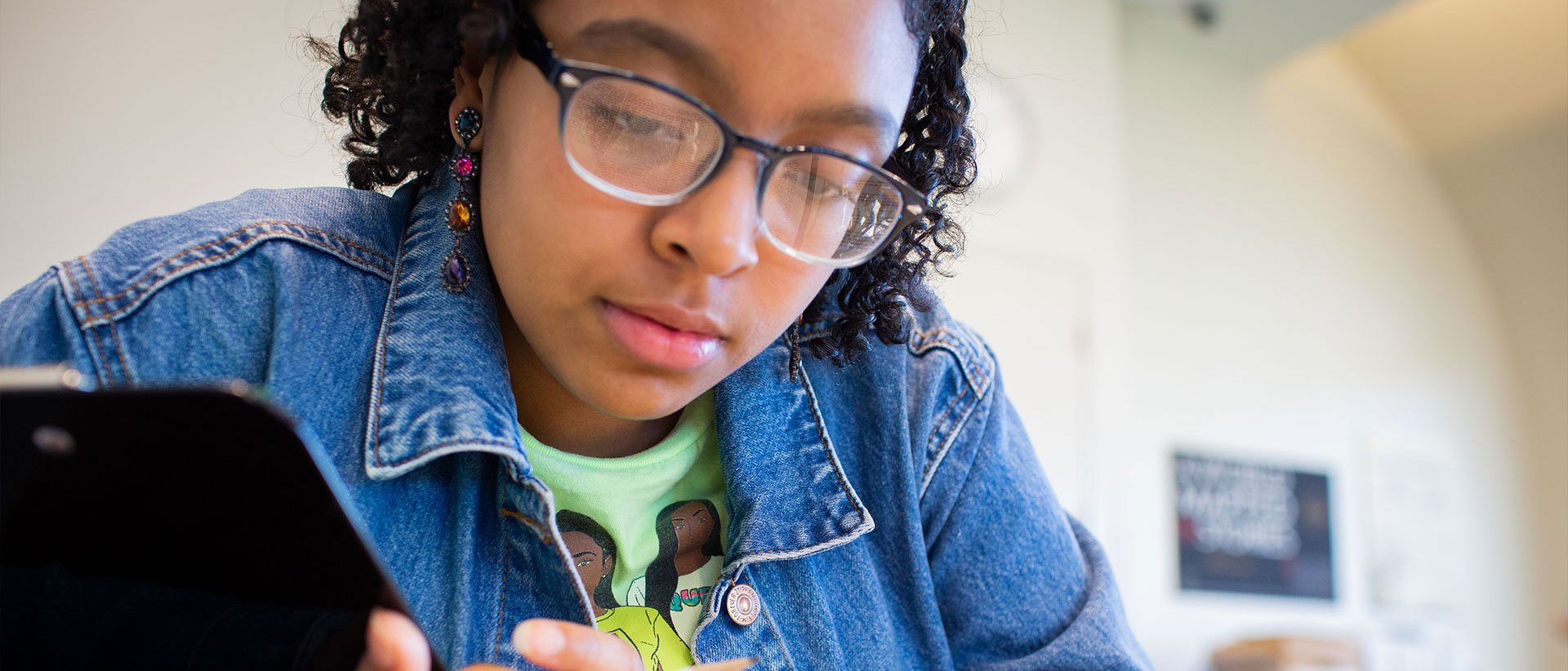 student looking down reading a book, which is reflected in her glasses