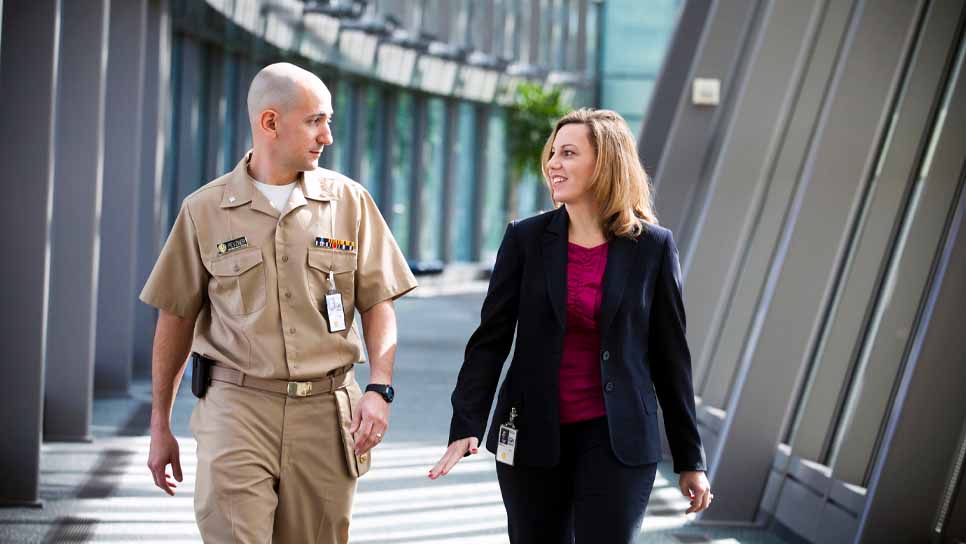 man in military uniform walking with woman researcher