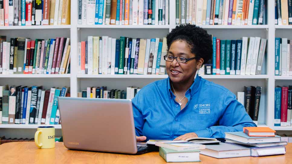 student working at a laptop in front of a bookcase