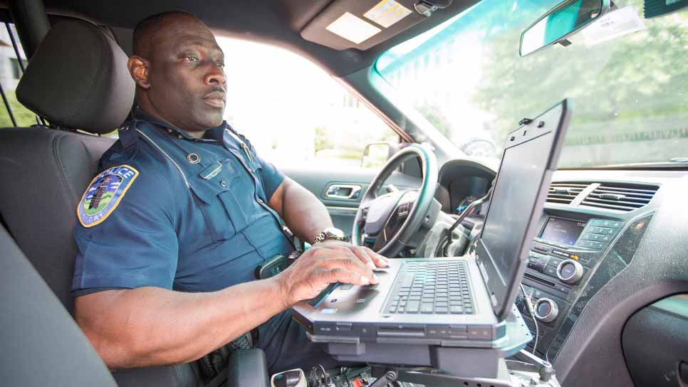 policeman working on laptop in patrol car