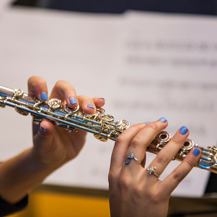 student hands with blue nail polish playing flute
