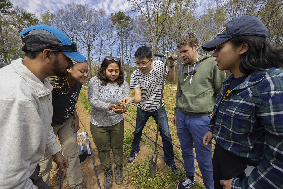 students and professors with shovels on a farm