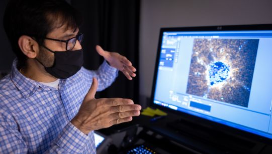 researcher in front of a computer monitor explaining what is happening on the screen